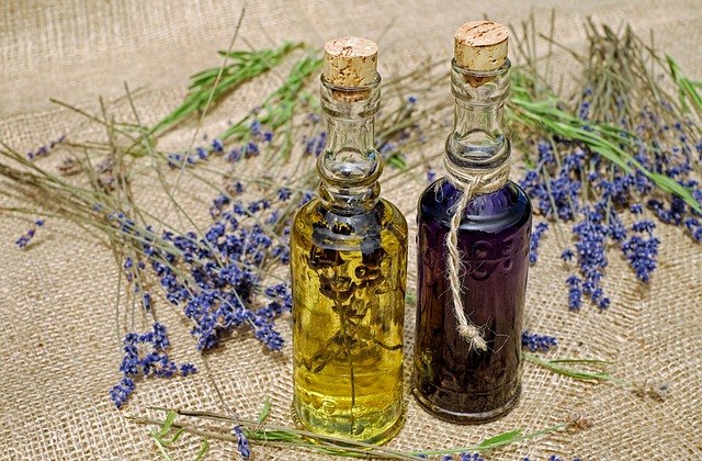 two small bottles of oils with lavender blooms placed around them.