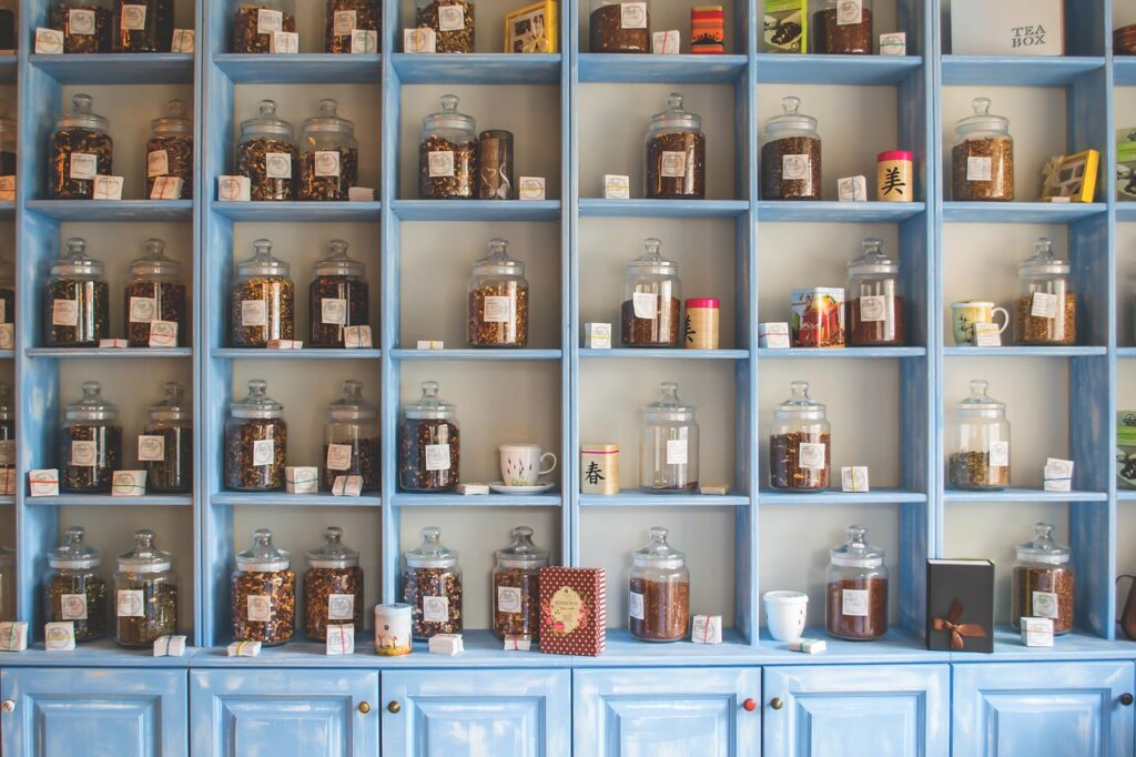 tall, blue shelves full of clear, glass jars filled with dried herbs and botanical matter.